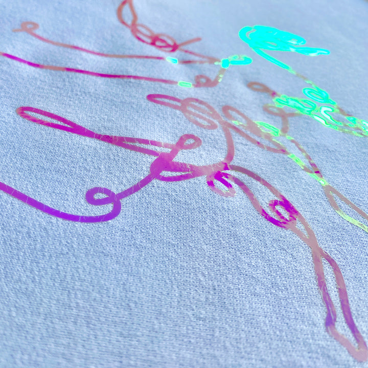 Side view of the light hitting the vinyl and reflecting in pink, purple, blue and green hues. On "bar cursive" white sweatshirt by DRYbands.