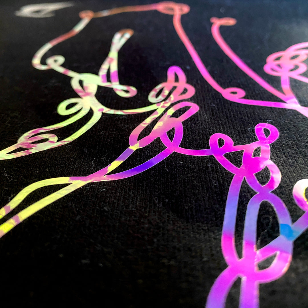 Side view of the light hitting the vinyl and reflecting in pink and purple hues. On "bar cursive" black sweatshirt by DRYbands.