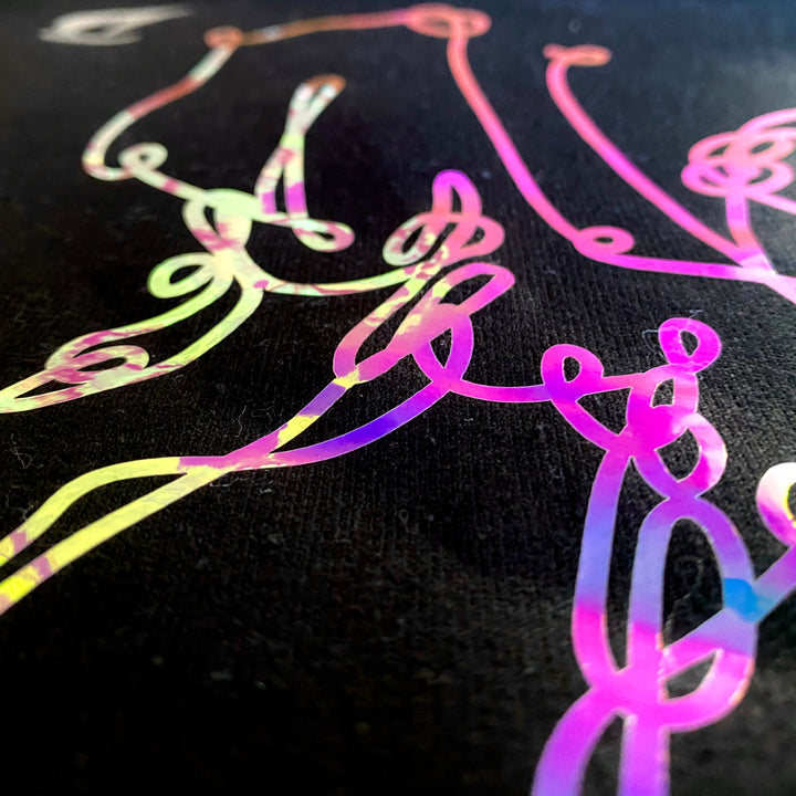 Side view of the light hitting the vinyl and reflecting in pink and purple hues. On "bar cursive" black sweatshirt by DRYbands.