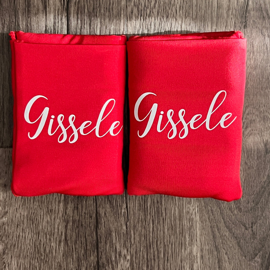 Two DRYbands, best wristbands for gymnasts, on a dark wood surface, each printed with the word 'Gissele' in white cursive script.