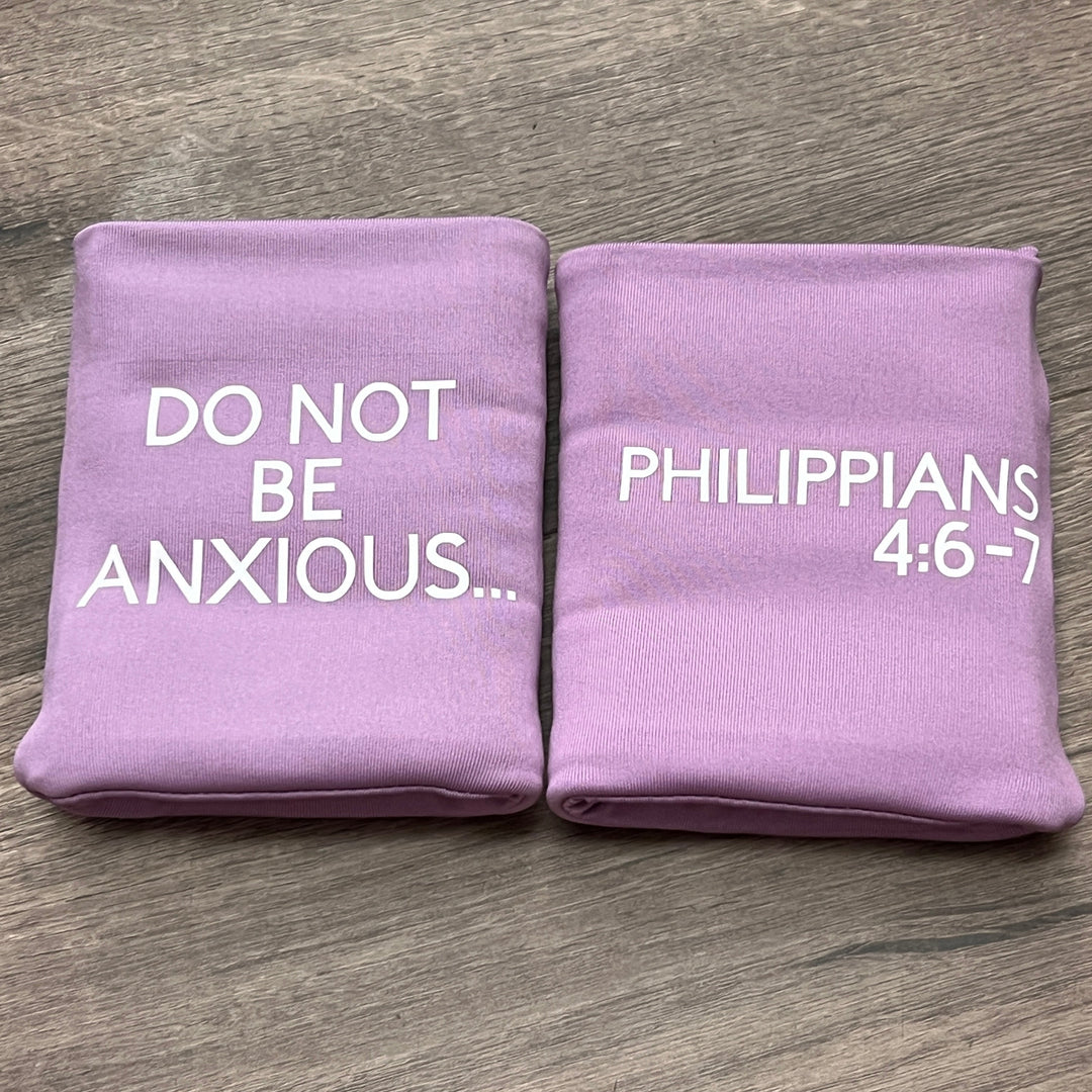 Two lavender purple DRYbands, best wristbands for getting rid of rips, with white printed text, placed side-by-side on a gray wood-textured surface. One bag reads 'DO NOT BE ANXIOUS.